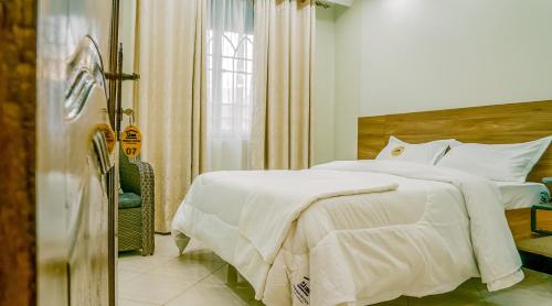 a bedroom with a white bed and a window at Neriah Suites in Kabale