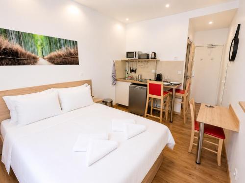 a bedroom with a white bed and a kitchen at Residence Akantha in Nice