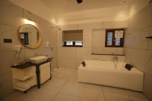 a white bathroom with a tub and a sink at The Mars Sphere in Dehradun