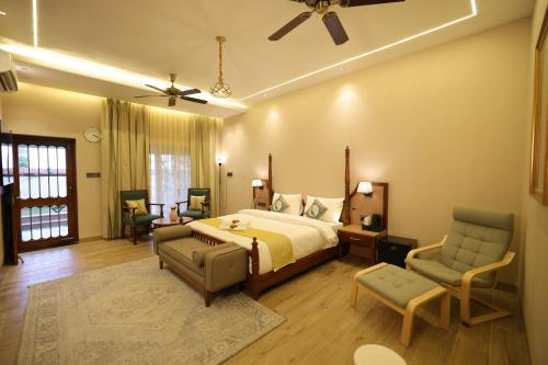 a bedroom with a bed and two chairs and a ceiling fan at The Mars Sphere in Dehradun