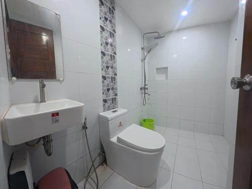 a white bathroom with a toilet and a sink at White Beach Resort Bar & Restaurant in Puerto Galera