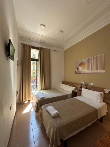 a hotel room with two beds and a window at Hostal Delfos in Barcelona