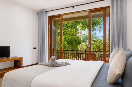 a bedroom with a large bed and a balcony at Darlina Hiriketiya in Hiriketiya