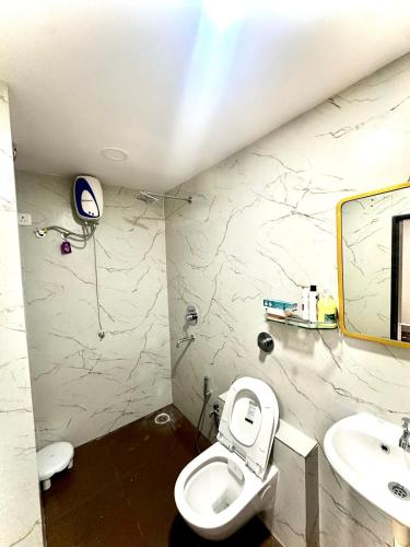 a bathroom with a toilet and a sink and a mirror at Cozy 2BHK with Balcony & Kitchen in Nagpur