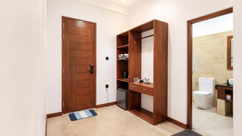 a bathroom with a toilet and a wooden door at Darlina Hiriketiya in Hiriketiya