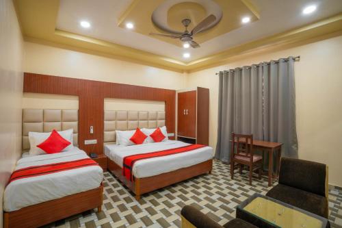 a hotel room with two beds and a desk at Hotel Kiaara in Varanasi