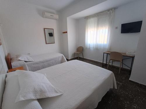 a hotel room with two beds and a table and a television at Pensíon Lucia in Casinos