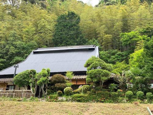a house with a metal roof in a forest at ゲストハウス やまんなか in Kamida