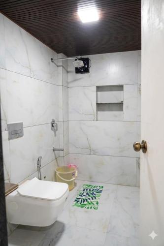 a white bathroom with a toilet and a shower at Gaikar Farm & Resort in Murbād