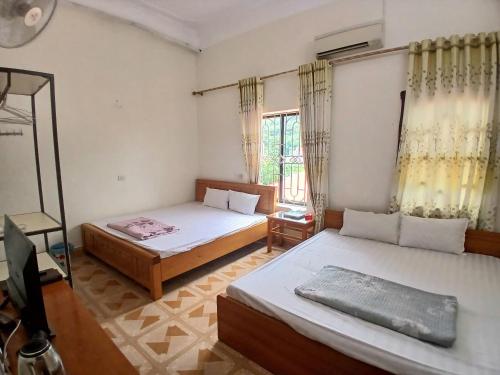 a bedroom with two beds and a television in it at Nhà nghỉ Homestay Minh Hạnh in Nà Phia