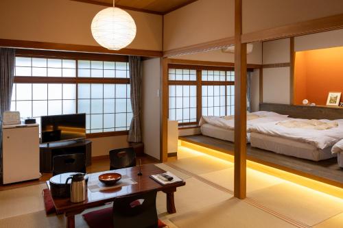 a bedroom with a bed and a desk and a table at Ryokan Warabino in Takayama