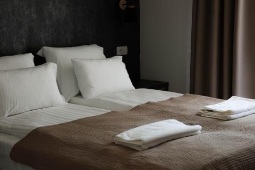 a bed with white sheets and two towels on it at Galerija Odzaci in Odžaci
