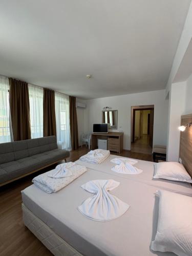 two beds in a large room with a couch at Къща за гости Екстаси in Primorsko