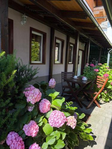 a patio with pink flowers and a wooden table at Rooms Ravnik in Bled