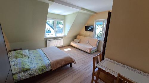 a bedroom with a bed and a chair and two windows at Noclegi pod Brzegiem in Zawoja