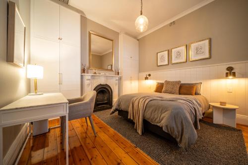 a bedroom with a bed and a table and a mirror at Wisteria Cottage circa 1880 in North Adelaide