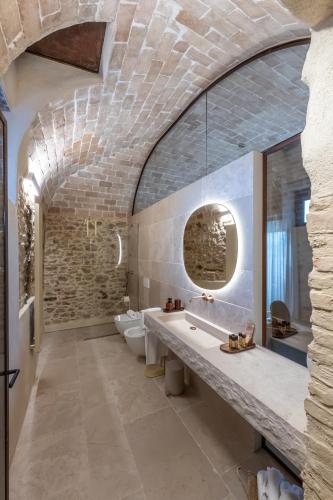 a bathroom with two toilets and a stone wall at Borgo Baccile by Vini Fantini in Crecchio