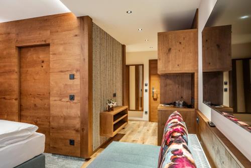 ein Schlafzimmer mit Holzwänden und einem Bett mit einer Couch in der Unterkunft Hotel Pramstraller in Mayrhofen