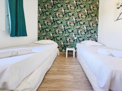 two beds in a room with a green wallpaper at L'atelier Lena, Calme, Confort, 10 min Disneyland in Montry