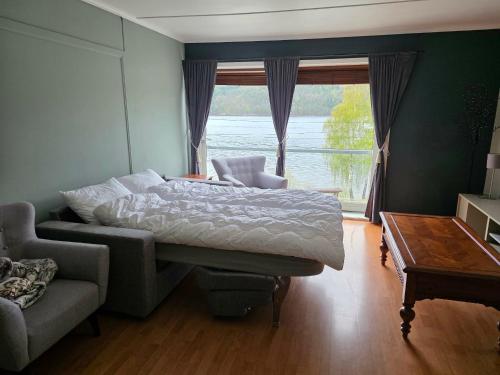 a bedroom with a bed and a couch and a window at Leilighet ved vannet in Konsmo