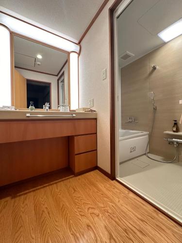 a bathroom with a mirror and a tub and a sink at Komatsu-kan Kofu-tei in Matsushima