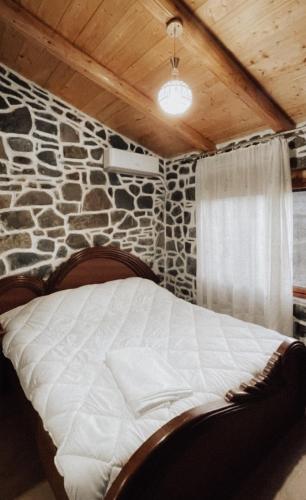 a bed in a room with a stone wall at VEIS Country House in Kamenicë