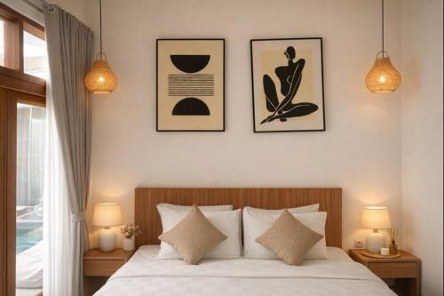 a bedroom with a bed with three pictures on the wall at Selena Home Tropical Villa Jimbaran in Jimbaran