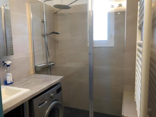 a bathroom with a shower and a washing machine at Appart avec terrasse proche mer in Macinaggio