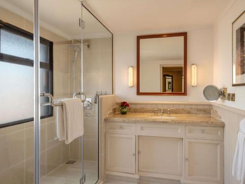 a bathroom with a shower and a sink and a mirror at Fairmont The Norfolk in Nairobi