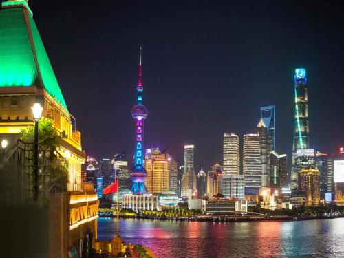 a view of a city at night with a river at Fairmont Peace Hotel on the Bund in Shanghai