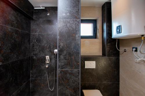 a bathroom with a shower with black tiles at Premium Apartments Zevs in Budva