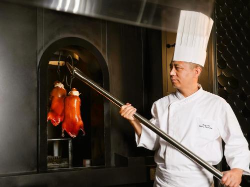 a chef holding a pole in a kitchen at InterContinental Beijing Sanlitun by IHG in Beijing