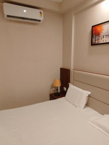 a bedroom with a white bed and a air conditioner at Velvet Nook in Greater Noida