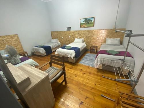 a room with three beds and a bench in it at Keetmanshoop Self-catering in Keetmanshoop