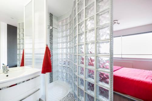 a bathroom with a glass walled shower and a bed at L'Horizon by Cocoonr in Rennes