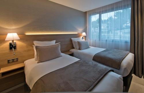 une chambre d'hôtel avec deux lits et une fenêtre dans l'établissement Golden Tulip Sophia Antipolis - Hotel & Spa, à Valbonne