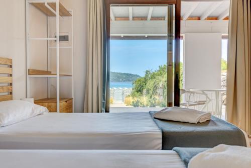 a bedroom with two beds and a view of the ocean at Hotel Delfino in Procchio