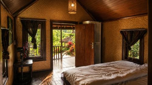 a bedroom with a bed in a room with windows at Tetebatu Garden Lombok in Tetebatu