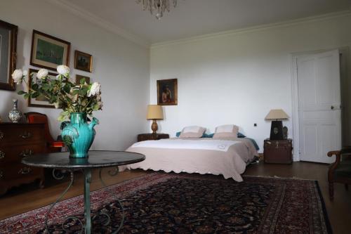a bedroom with a bed and a vase of flowers on a table at Chambre d'hôtes chez Johannes et Adèle in Brive-la-Gaillarde