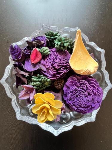 a bowl of purple and yellow flowers on a table at Luna Spaces-Riva Nr KIMS Hospital, Bayer House, TCS thane in Thane