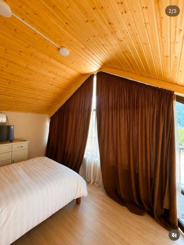 a bedroom with a bed and a large window at Mountain Shadow Racha in Ambrolauri