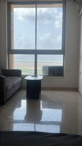 a living room with a table in front of a large window at Luna Spaces-Riva Nr KIMS Hospital, Bayer House, TCS thane in Thane