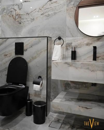 a bathroom with a black toilet and a mirror at THE VIEW chalet in Makhrabā