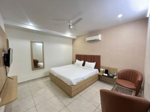 a bedroom with a bed and a chair and a mirror at Vida Hotel in Patiāla