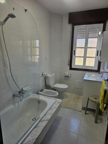 a bathroom with a tub and a toilet and a sink at Casa A devesa in Cangas de Morrazo