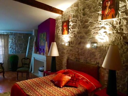 a bedroom with a red bed and a stone wall at La Maison dans les remparts in Aigues-Mortes