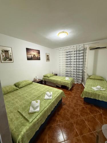 two beds in a room with green sheets at Apartman Marković in Meljine