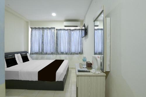 a bedroom with a bed and a desk with a computer at Collection O Axlite Hotel in Taiping