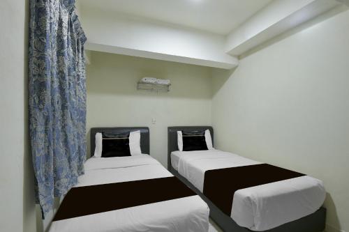 two beds in a small room with curtains at Collection O Axlite Hotel in Taiping