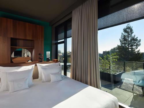 a bedroom with a bed and a large window at L'Esquisse Hotel & Spa Colmar - MGallery Collection in Colmar
